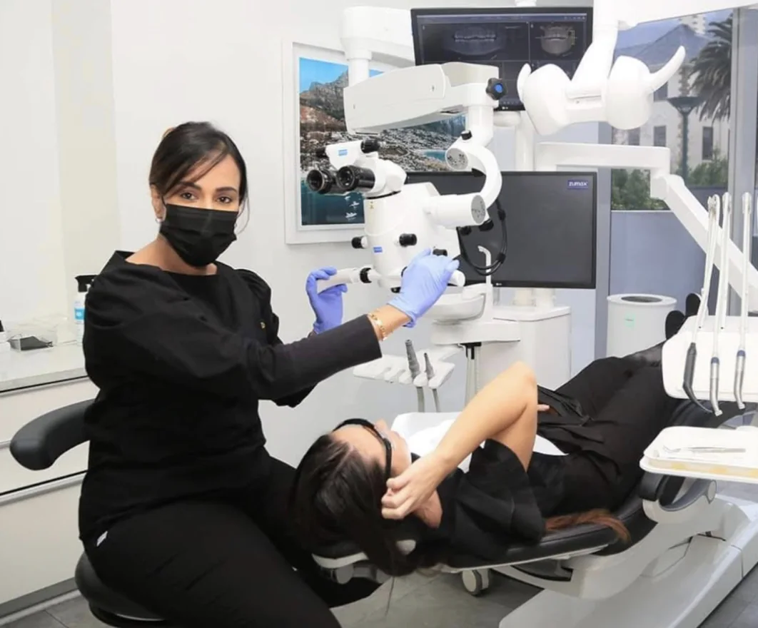 Dr Nivy Singh at the dental microscope with a patient in the chair