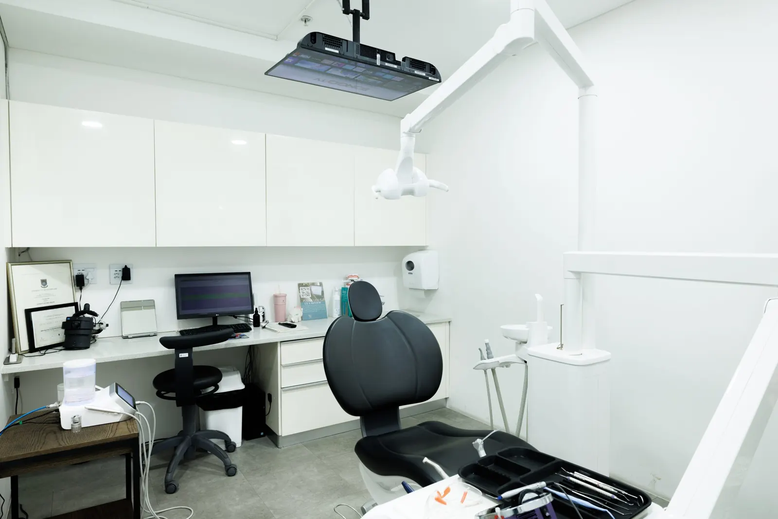 A second treatment room with a dental chair and overhead screen