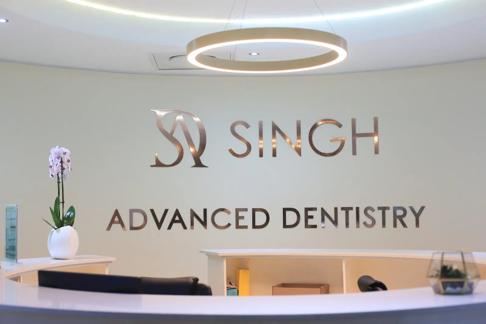 Reception at Singh Advanced Dentistry, with the rose-gold logo on the wall